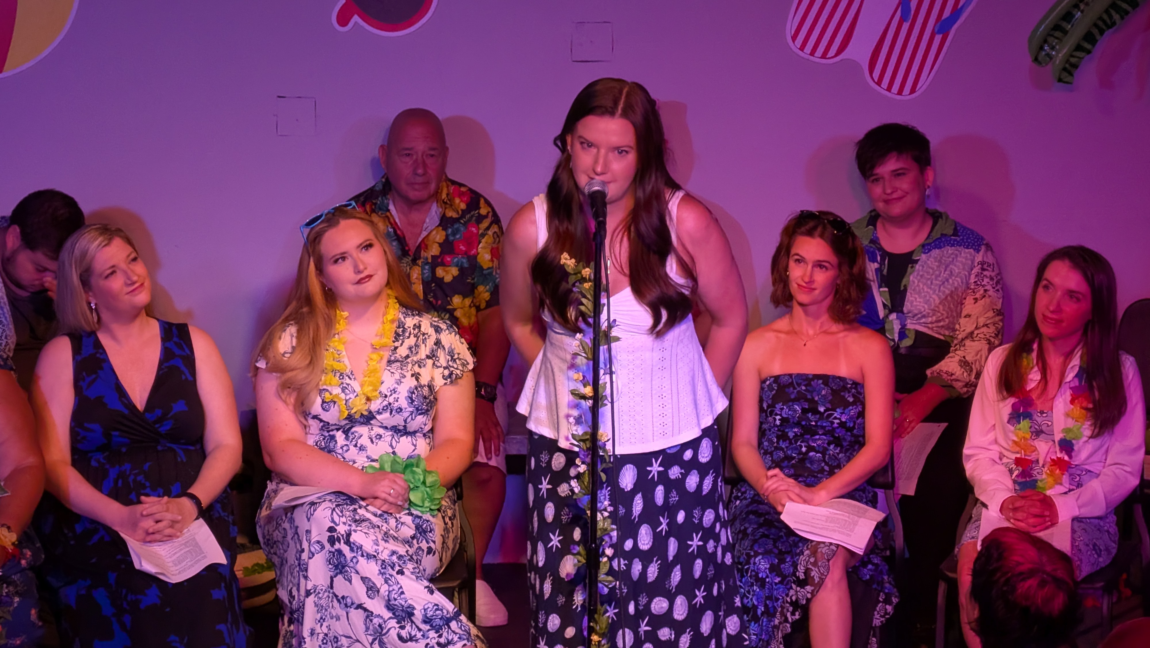A singer at the center microphone with pink wash lighting.