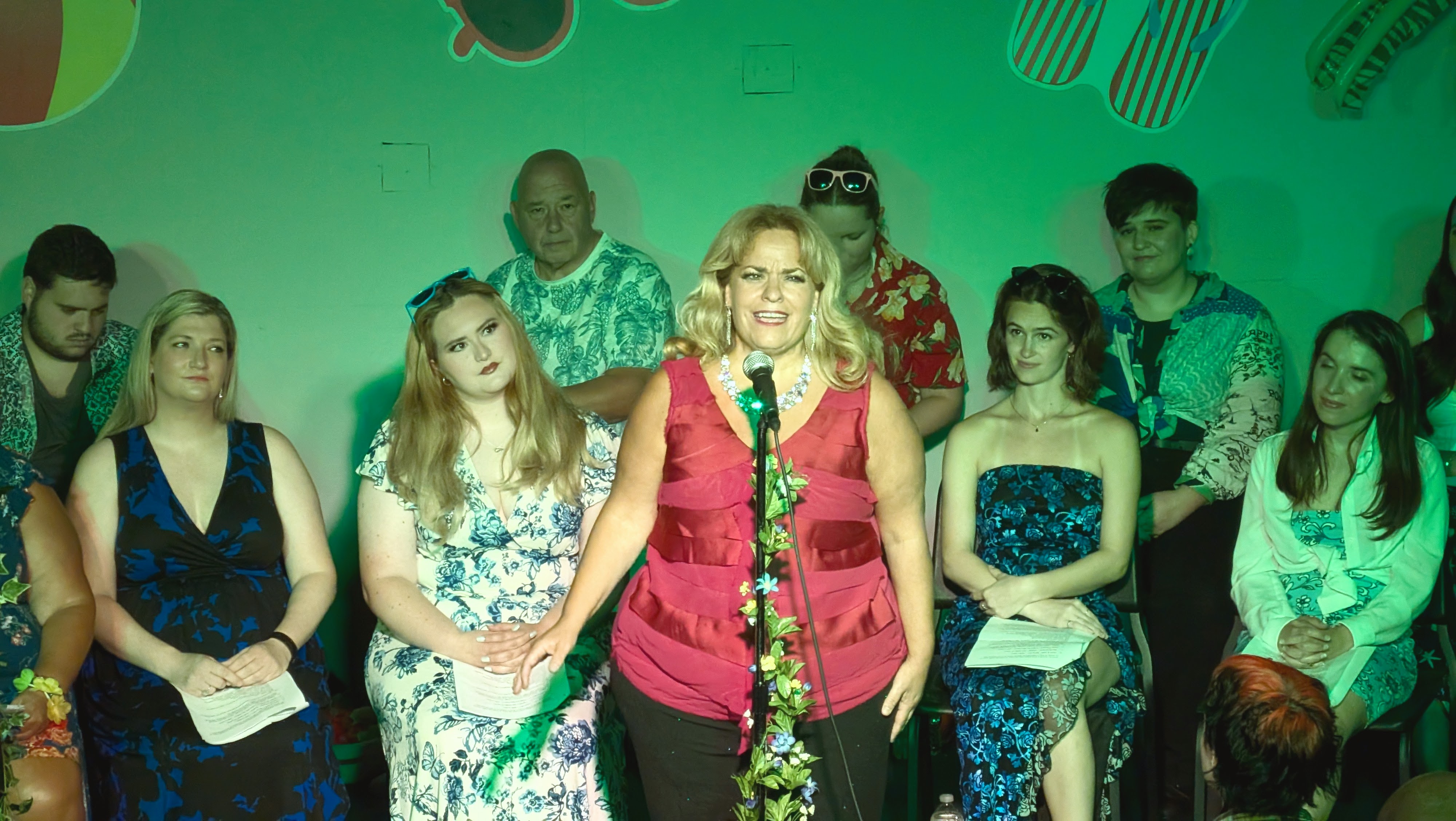 A singer at the center microphone with green wash lighting.